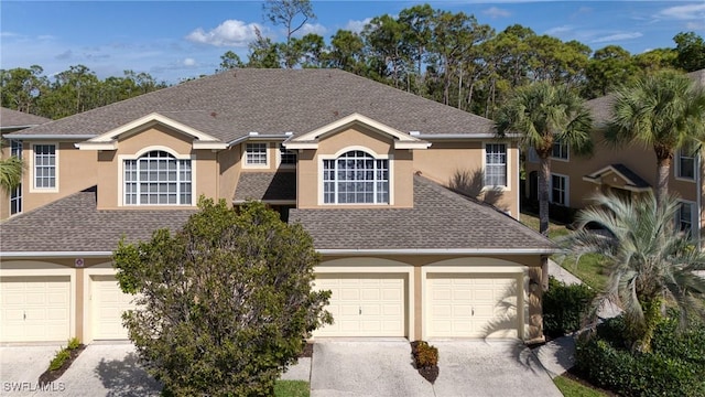 view of front of property featuring a garage, concrete driveway, roof with shingles, and stucco siding