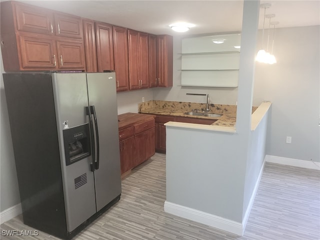 kitchen featuring sink, stainless steel fridge with ice dispenser, light hardwood / wood-style flooring, kitchen peninsula, and pendant lighting