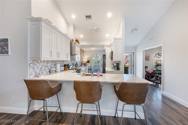 5858 Westbourgh Ct, Naples, FL 34112 - kitchen with a breakfast bar, visible vents, white cabinetry, and a peninsula