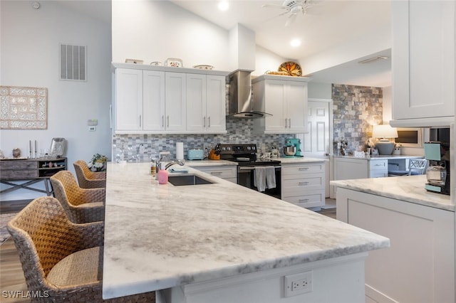 5858 Westbourgh Ct, Naples, FL 34112 - kitchen with electric range, a breakfast bar area, a peninsula, white cabinetry, and a sink