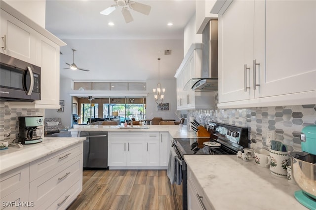5858 Westbourgh Ct, Naples, FL 34112 - kitchen with wall chimney range hood, white cabinetry, stainless steel appliances, and decorative light fixtures