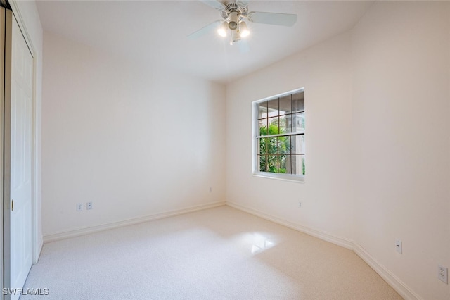 unfurnished room with a ceiling fan, light carpet, and baseboards