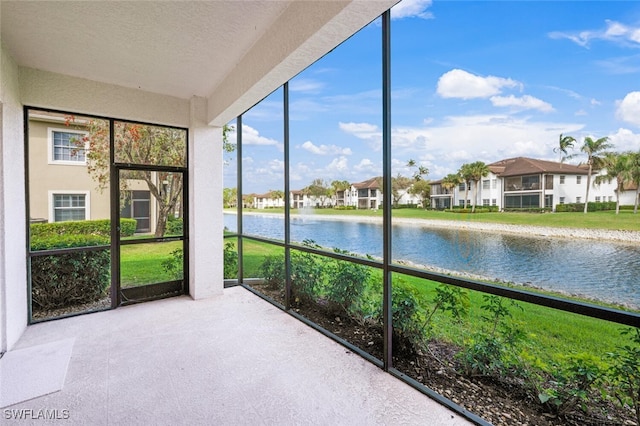 unfurnished sunroom featuring a water view and a residential view