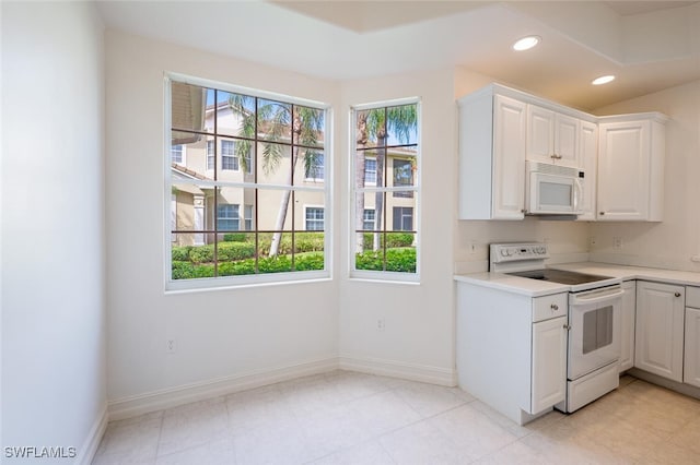 kitchen with light countertops, white appliances, white cabinetry, and recessed lighting