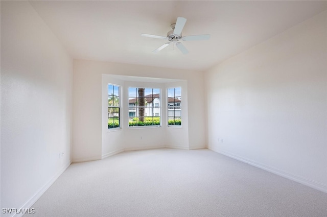 spare room with light carpet, baseboards, and a ceiling fan