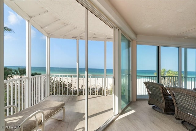 sunroom / solarium featuring a water view and a beach view