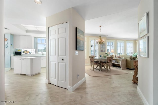 interior space with white cabinetry, open floor plan, light countertops, a tray ceiling, and pendant lighting