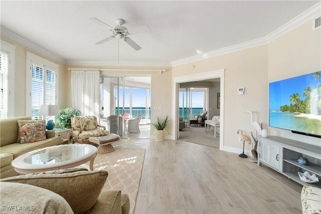 living room with visible vents, ornamental molding, a ceiling fan, light wood-type flooring, and baseboards