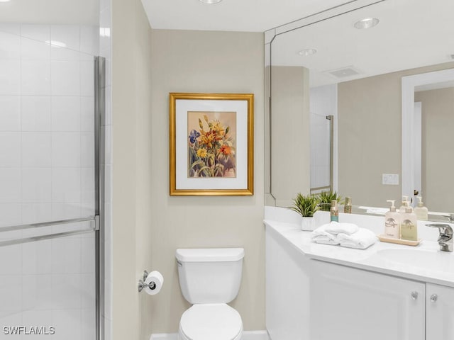 bathroom featuring vanity, a shower with shower door, and toilet