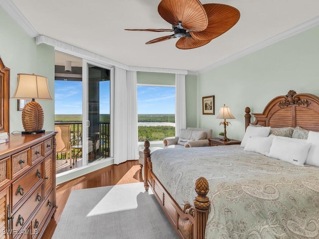 bedroom with crown molding, hardwood / wood-style floors, access to exterior, and a wall of windows