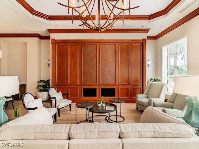 living room with crown molding, a tray ceiling, a chandelier, and light wood-type flooring