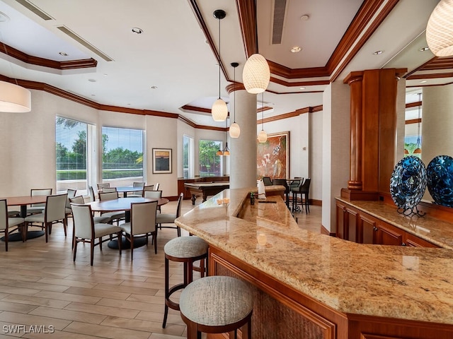 bar with crown molding, decorative light fixtures, and decorative columns