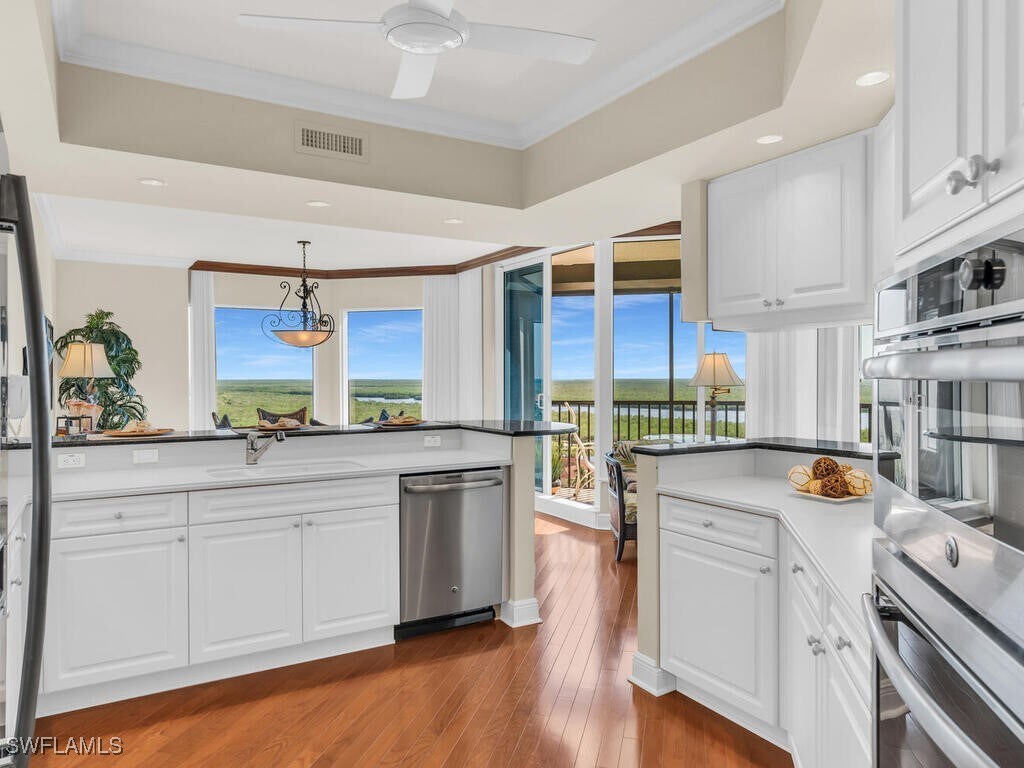 1060 Borghese Ln Unit 1002, Naples, FL 34114 - kitchen with stainless steel appliances, a sink, white cabinets, and crown molding