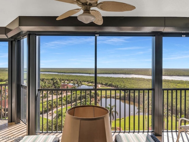 unfurnished sunroom with ceiling fan and a water view