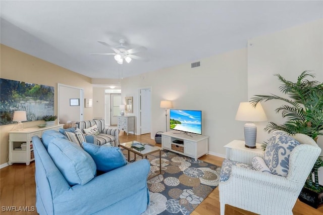 living area with baseboards, wood finished floors, visible vents, and ceiling fan