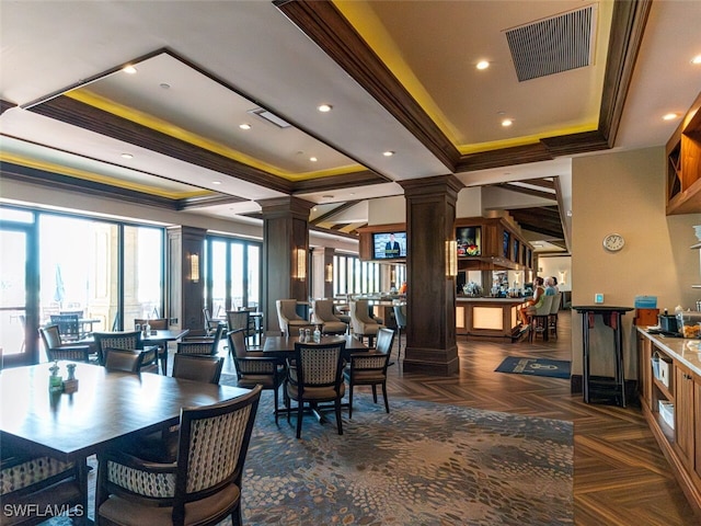 dining space featuring a tray ceiling, visible vents, crown molding, and ornate columns