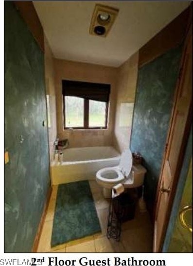 bathroom featuring a bathing tub, tile patterned flooring, and toilet