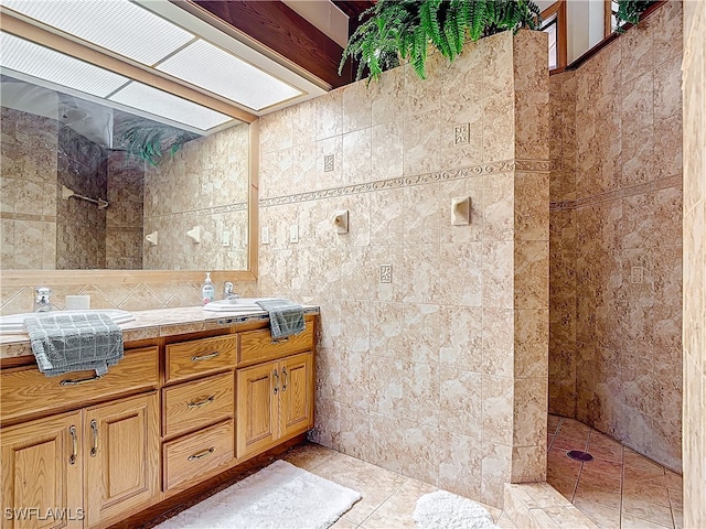 full bathroom with a skylight, walk in shower, tile walls, and vanity