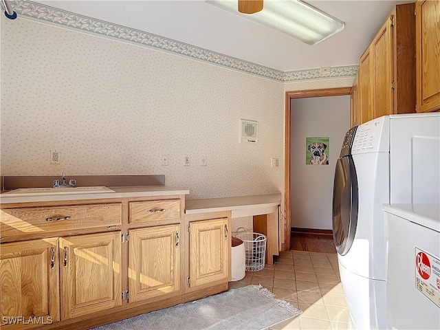 clothes washing area with cabinet space, light tile patterned floors, a sink, and wallpapered walls