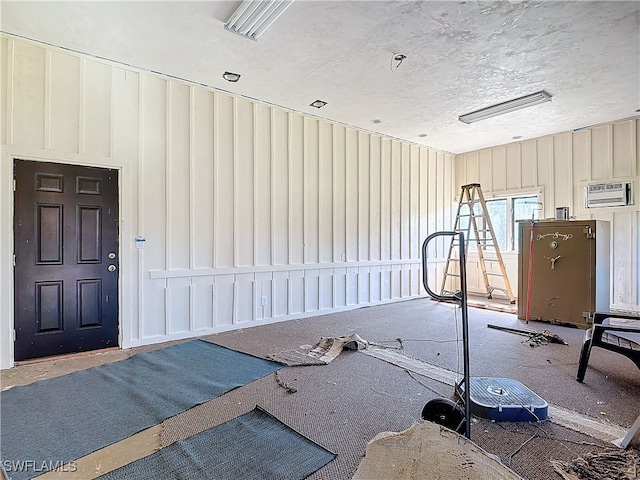 interior space with a textured ceiling and a wall unit AC