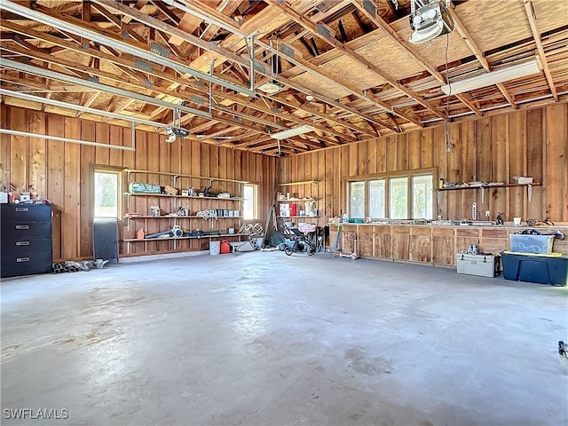 garage featuring wooden walls, a workshop area, and a garage door opener
