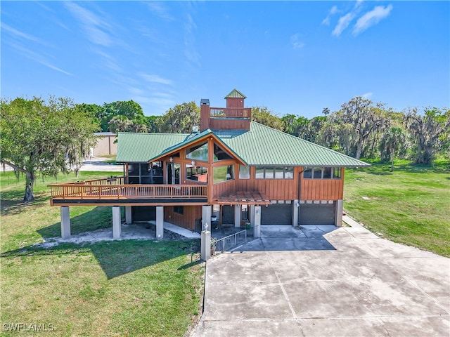 view of front of home featuring metal roof, driveway, a front lawn, and an attached garage