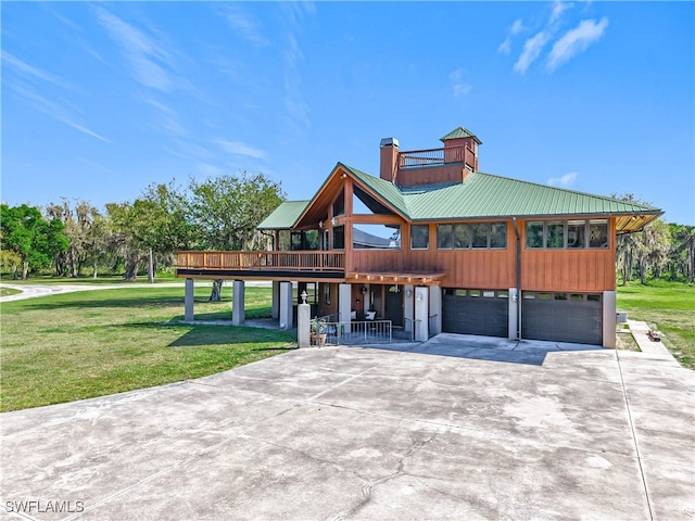 view of front facade featuring a chimney, metal roof, a garage, driveway, and a front lawn