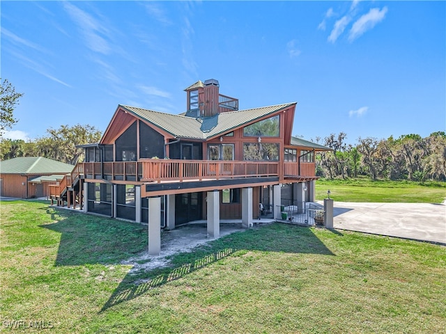 rear view of house with a deck, metal roof, a sunroom, a yard, and driveway