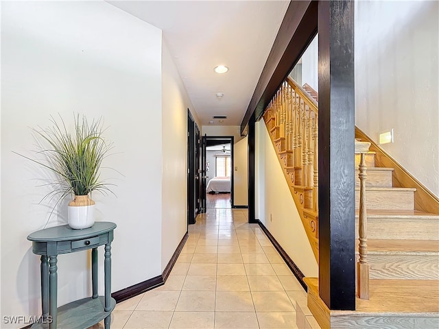 hall with stairs, light tile patterned flooring, and baseboards