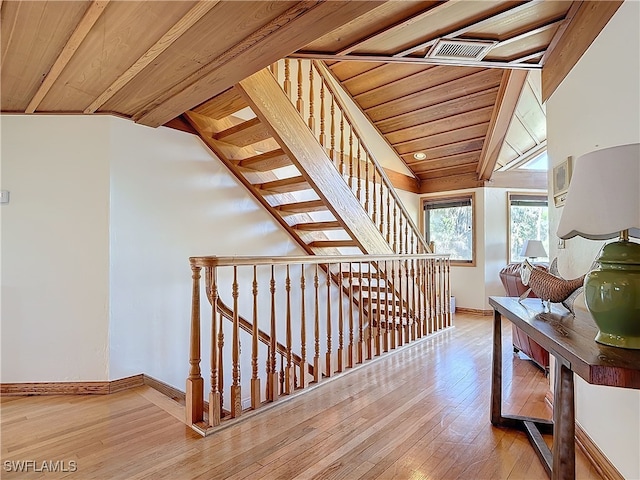 staircase featuring lofted ceiling, wood ceiling, baseboards, and hardwood / wood-style floors