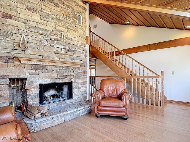 living area with vaulted ceiling with beams, stairs, a fireplace, and wood finished floors
