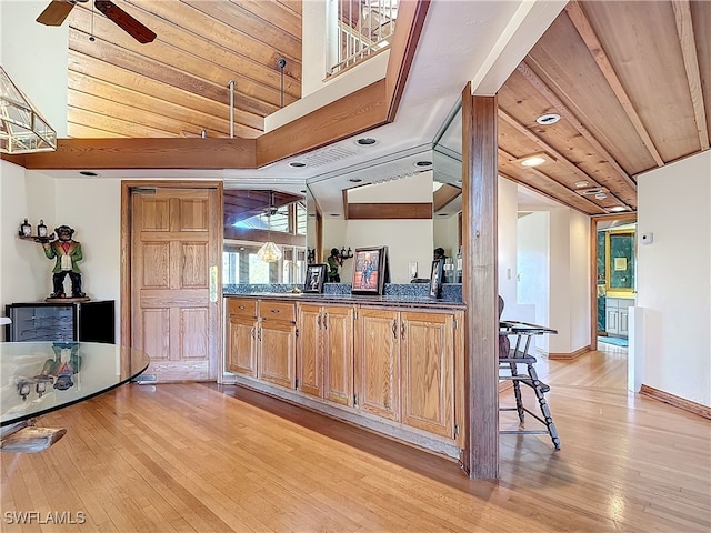 kitchen with dark countertops, light wood-style floors, vaulted ceiling, ceiling fan, and wooden ceiling