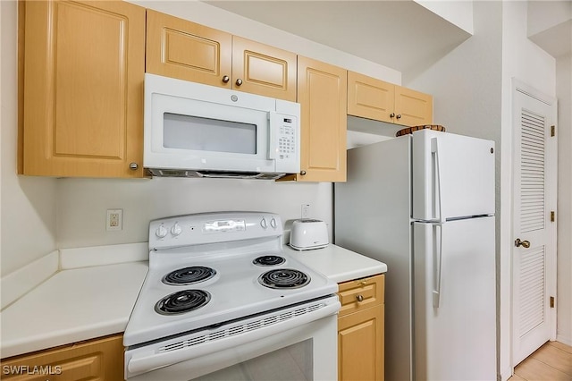 kitchen with light brown cabinetry, white appliances, and light countertops