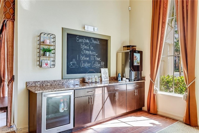 bar with baseboards, beverage cooler, and light wood finished floors