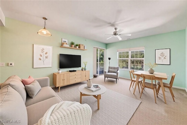 living room with light carpet, baseboards, and ceiling fan