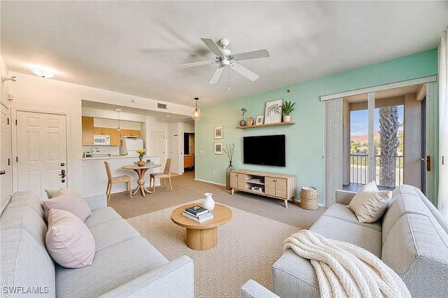 living room with visible vents, baseboards, light colored carpet, and a ceiling fan