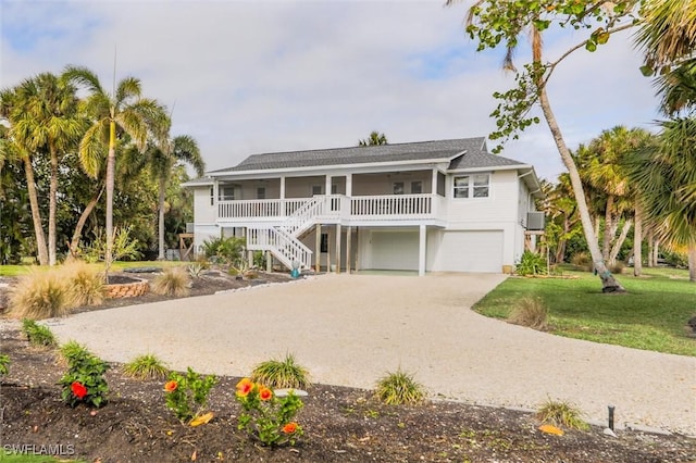 beach home featuring a garage, a front yard, and covered porch