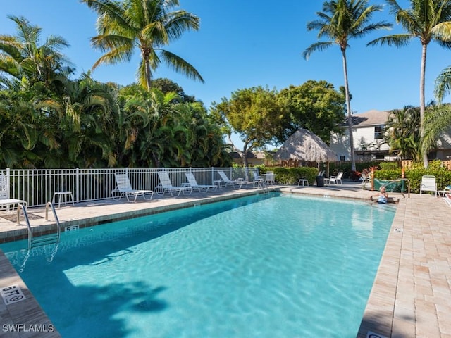 community pool with a patio area and fence