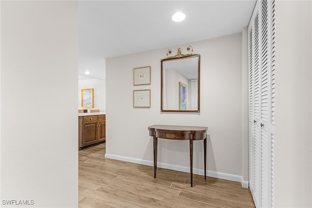 hallway with baseboards, recessed lighting, and light wood-style floors