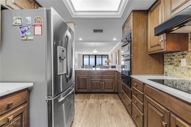 kitchen featuring tasteful backsplash, visible vents, light wood-style floors, under cabinet range hood, and black appliances