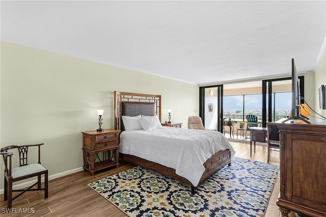 bedroom with wood finished floors, baseboards, access to outside, ornamental molding, and expansive windows