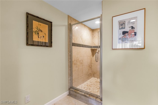 bathroom featuring tile patterned flooring, a shower stall, and baseboards