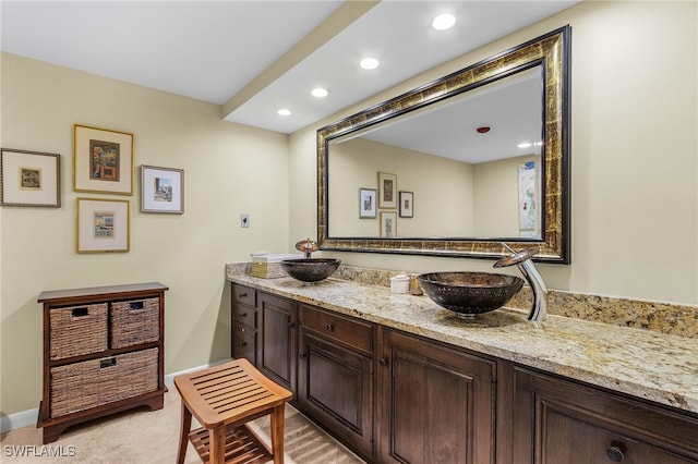 bathroom with baseboards, double vanity, a sink, and recessed lighting