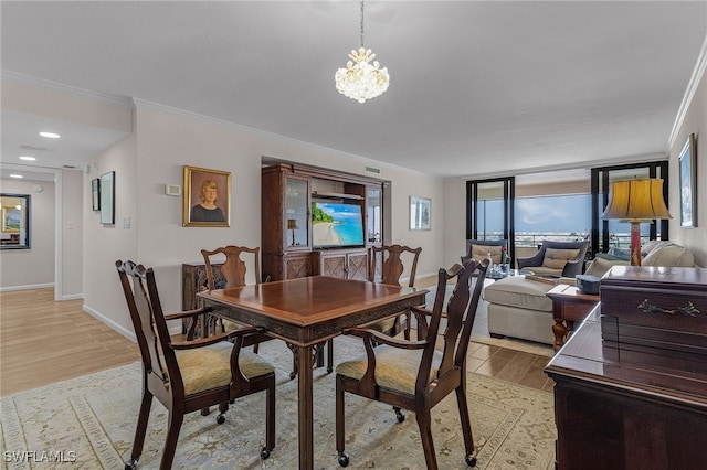 dining space with light wood-style floors, baseboards, crown molding, and an inviting chandelier