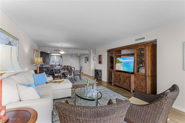 living room with visible vents, crown molding, baseboards, and wood finished floors