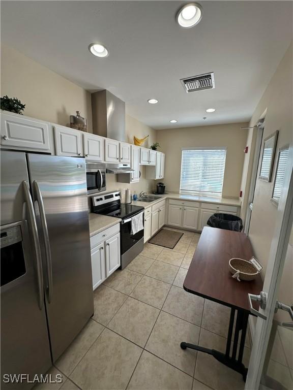 kitchen with light tile patterned floors, visible vents, light countertops, appliances with stainless steel finishes, and under cabinet range hood