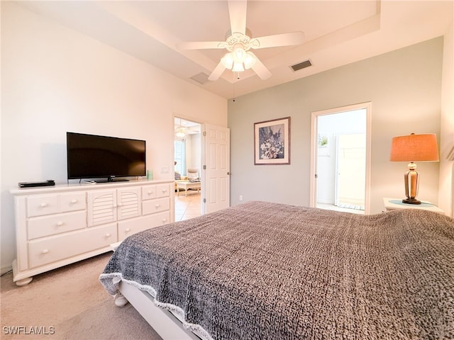 bedroom with light carpet, ceiling fan, a tray ceiling, and visible vents