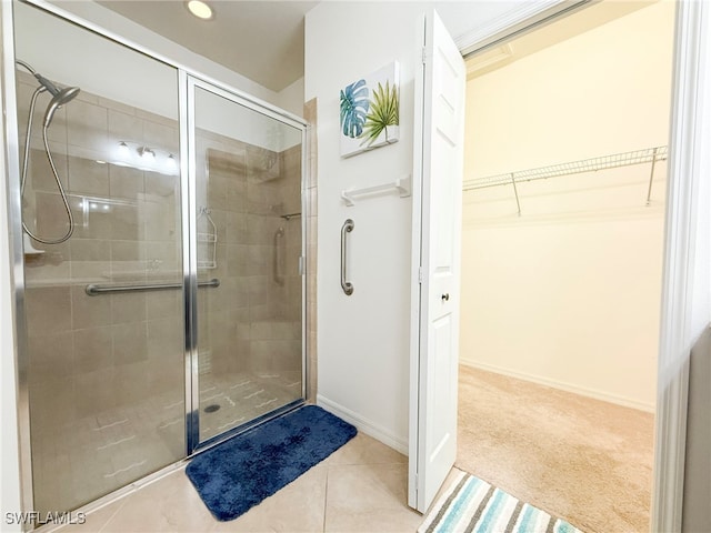 full bath featuring a spacious closet, tile patterned flooring, a shower stall, and baseboards