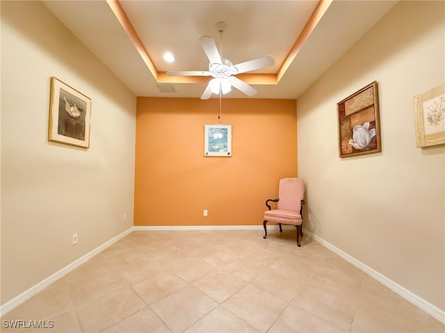 unfurnished room with light tile patterned floors, baseboards, a tray ceiling, and ceiling fan