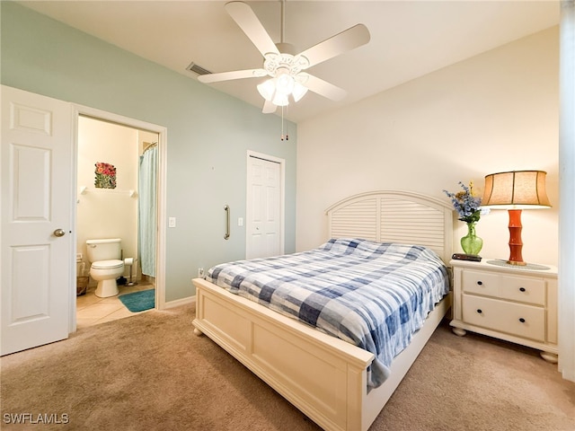 bedroom with light carpet, visible vents, baseboards, a ceiling fan, and ensuite bath